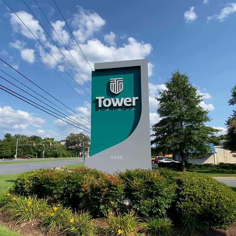 Tall, three-dimensional monument sign in grey and teal to mark the Tower Federal Credit Union business entrance and address.