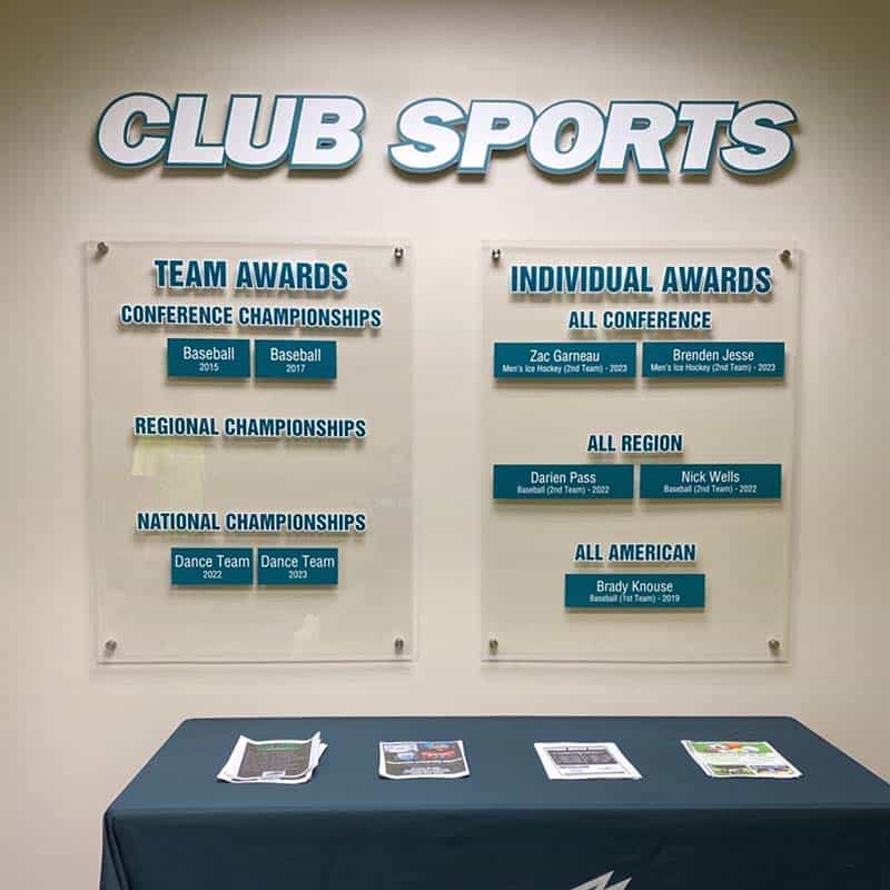 clear acrylic recognition signs mounted to a wall and imprinted with sporting awards for team and individual championship wins