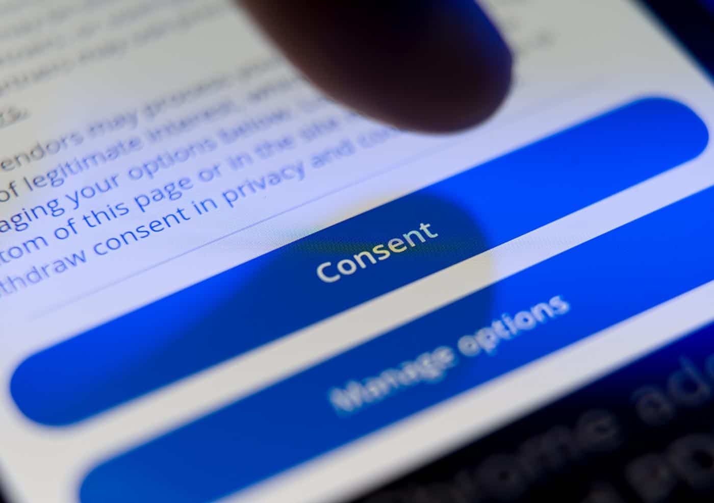 Finger tapping “Consent” on a website cookie pop-up.